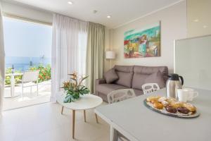 a living room with a couch and a table with a plate of food at Klayman Diamond Aparthotel in Acantilado de los Gigantes
