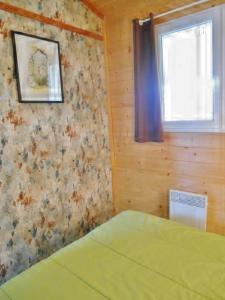 Un dormitorio con una cama verde y una ventana en Chalet Relais du Temple, en Mornans