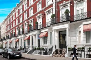 un hombre caminando por una calle en frente de un edificio en Heeton Concept Hotel - Kensington London, en Londres
