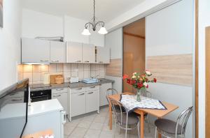 una cucina con armadi bianchi e un tavolo con fiori di Apartments Joko 1160 a Pola (Pula)