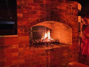 una mujer parada frente a una chimenea de ladrillo en Willuna Sanctuary en Chiltern