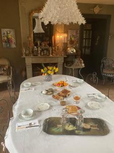 La Demeure du Collectionneur في Quintin: طاولة عليها قماش الطاولة البيضاء مع الطعام