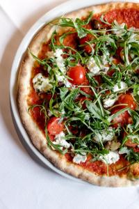 a pizza sitting on a plate on a table at Hotel Schmuckhof in Chiusa