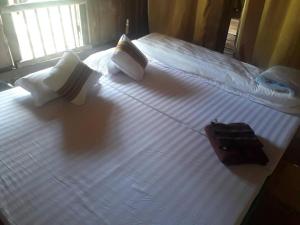 ein weißes Bett mit zwei Kissen und einer Tasche darauf in der Unterkunft Homestay Nguyễn Huệ in Làng Mõ
