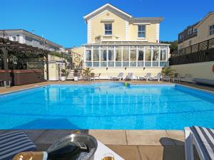 a large blue swimming pool in front of a house at Riviera Lodge Hotel in Torquay