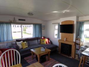 a living room with a couch and a table at Happydaze Caravan in Bacton