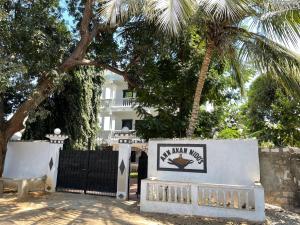ein Schild vor einem weißen Haus mit einer Palme in der Unterkunft ANN AKAN NIDO’S in Malindi