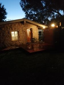 a small stone house with a patio at night at Maunder Cottage in Aldinga