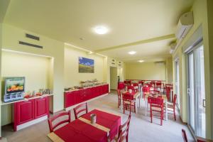a restaurant with red tables and chairs in a room at Hotel Foresteria in Volterra