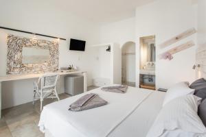 a white bedroom with a bed and a desk at Irini Rooms in Naousa