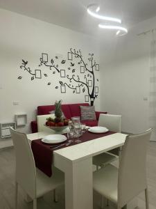 uma mesa de jantar com cadeiras e uma árvore na parede em Le Case di Lory em Lecce