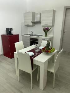 a white table and chairs with a bowl of fruit on it at Le Case di Lory in Lecce