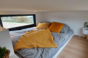 a bed in a small room with yellow pillows at Winzig Wohnen Tiny House Frigg direkt am Weserstrand in Elsfleth