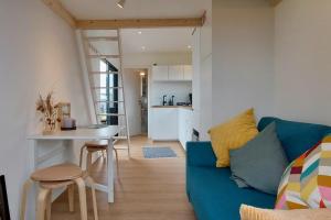 a living room with a blue couch and a kitchen at Winzig Wohnen Tiny House Frigg direkt am Weserstrand in Elsfleth