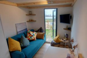 a living room with a blue couch and a sliding glass door at Winzig Wohnen Tiny House Frigg direkt am Weserstrand in Elsfleth