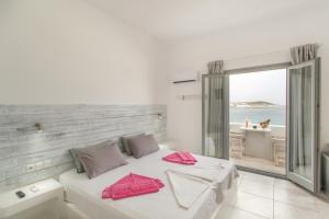 a bed room with a white bedspread and a large window at Irini Rooms in Naousa
