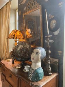 une statue sur une commode avec un miroir et une lampe dans l'établissement La Demeure du Collectionneur, à Quintin