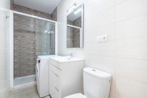 a white bathroom with a toilet and a sink at Bacana 3-3 Apartment Levante Beach in Benidorm
