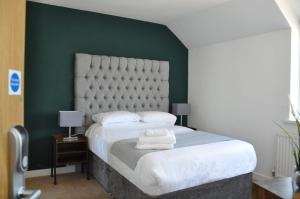 a bedroom with a large bed with a green wall at The Lodge by Cefn Tilla in Usk