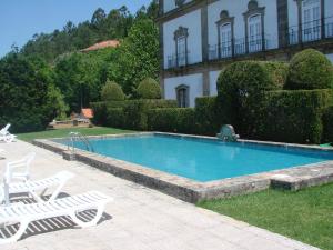 a swimming pool in front of a house with two lawn chairs at Casa das Torres da Facha in Ponte de Lima