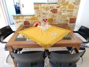 a wooden table with a yellow table cloth on it at Dimitris Vaso’s Villa with Sea and Mountain View! in Aliveri