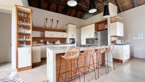 a kitchen with white cabinets and a bar with stools at Jacana River Lodge Mjejane Game Reserve in Hectorspruit