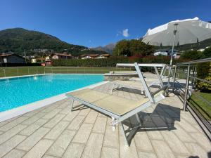 a chair and an umbrella next to a swimming pool at Residence Villa Paradiso in Gravedona