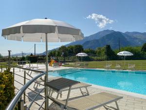 una piscina con tavolo, ombrellone e sedie di Residence Villa Paradiso a Gravedona