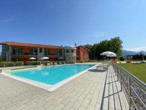 uma piscina com cadeiras e guarda-sóis ao lado de um edifício em Residence Villa Paradiso em Gravedona