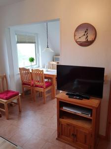 a living room with a television and a table with chairs at Lüttjes Diekhuus in Butjadingen OT Tossens