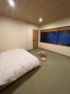 Un dormitorio con una gran cama blanca y una mesa en 城崎温泉 小宿 紬 tsumugi, en Toyooka