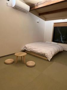 ein Schlafzimmer mit einem Bett, einem Tisch und zwei Hockern in der Unterkunft 城崎温泉 小宿 紬 tsumugi in Toyooka