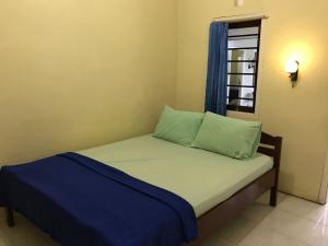 Cama pequeña en habitación con ventana en OYO 90998 Wisma Pinggir, en Tanjung Pinang