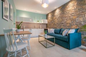 a living room with a blue couch and a kitchen at Αngelikon Luxurious Apartments in Agios Ioannis Kaspaka