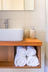 a shelf with towels and a sink in a bathroom at Aloustina Apartments in Archangelos +21 photos