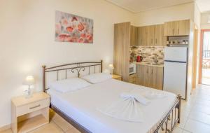 a bedroom with a large white bed and a kitchen at Aloustina Apartments in Archangelos