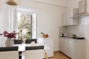 a kitchen with white cabinets and a white table at Salt & Sun Apartments by Konnect, at Kaminaki Beach in Nisakion