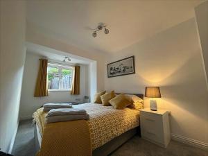 a bedroom with a bed and a lamp and a window at Cotswold apartment with private parking! in Stow on the Wold
