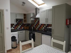 a kitchen with white cabinets and a stove top oven at Barn Owl in Happisburgh