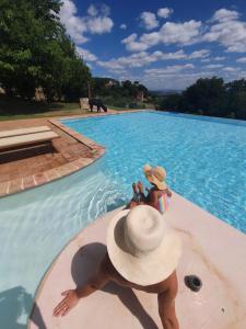 une femme dans un chapeau assise dans une piscine dans l'établissement Agriturismo Il Vecchio Mandorlo, à Pérouse