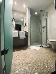 uma casa de banho com um chuveiro, um lavatório e um WC. em AiREA Hotel em Büren