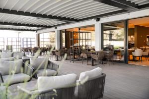 un restaurante con sillas blancas, mesas y ventanas en Elegans Hotel Brdo en Kranj