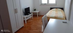 um quarto com uma cama, uma mesa e uma televisão em Apartmani Barišić em Trogir