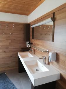 baño con lavabo blanco y paredes de madera en Haus Petra, en Neumarkt in Steiermark