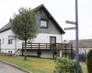 a white and black house with a tree and a street sign at Haus Herrloch in Hermeskeil