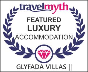 a logo of a laurel wreath with a pink diamond at Glyfada Villas || in Paralion astros