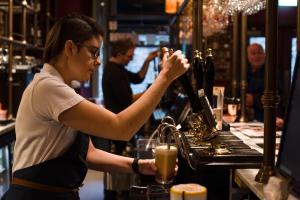 a woman preparing a drink at a bar at The Temperance Inn, Ambleside - The Inn Collection Group in Ambleside