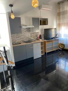 a kitchen with a black tile floor and a tv at Charmant studio proche mer in Nice