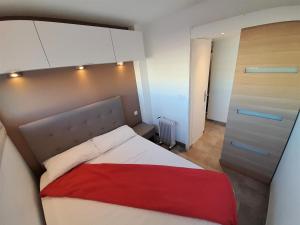 a bedroom with a bed with a red blanket at Appartement Sky & Sand Village Naturiste in Cap d'Agde