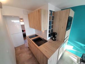 una cocina con armarios de madera y fregadero en Appartement Sky & Sand Village Naturiste, en Cap d'Agde